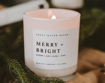 May include: White candle with a frosted glass jar and a label that reads "Sweet Water Decor Merry + Bright Bayberry + Clove + Nutmeg + Cedar Net Wt 237 g | Made in USA | 11 oz Candle"