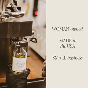 May include: A clear glass bottle filled with yellow liquid labeled Pumpkin Spice being filled by a metal machine. The text on the right side reads WOMAN-owned, MADE in the USA, and SMALL business in a serif font on a light beige background.