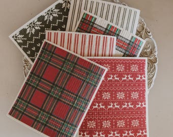 May include: A collection of rectangular cleaning cloths featuring various patterns including red and green plaid, red with white reindeer and snowflake motifs, black with white snowflake designs, and vertical stripes in red or black on white backgrounds.
