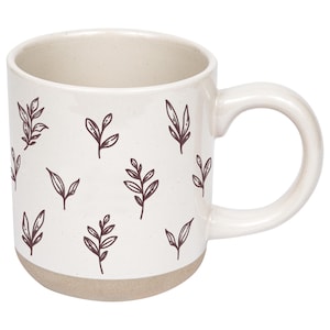 May include: A white ceramic mug with a beige base and handle. The mug is decorated with a repeating pattern of dark brown leaf illustrations. The mug is designed for hot beverages.