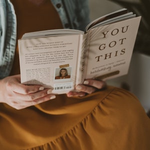 May include: A pink and white book with the title "You Got This" in brown text. The book is open and the back cover features a photo of a woman with the text "How can women keep up with life's demands without forgetting who God created them to be?"