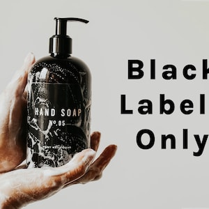 K&ouml;nnte beinhalten: Eine schwarze Flasche Handseife mit einem wei&szlig;en Etikett, auf dem "HAND SOAP NO. 05 SWEET WATERMELON" steht. Die Flasche wird von zwei H&auml;nden gehalten.