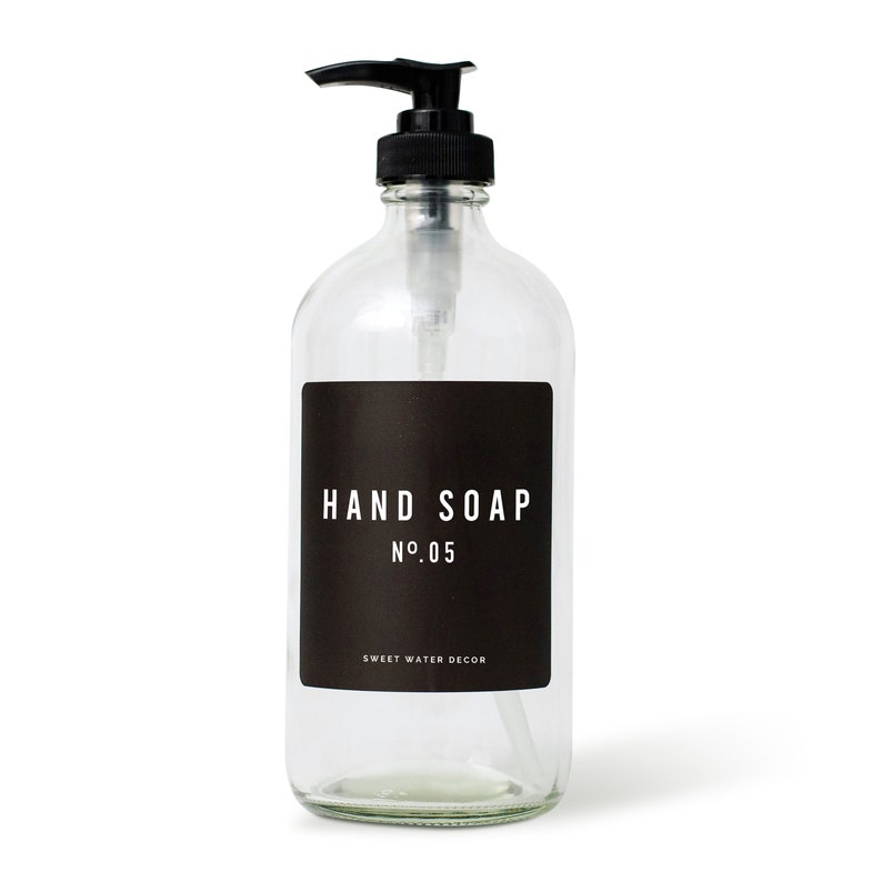 K&ouml;nnte beinhalten: Eine klare Glasflasche mit einem schwarzen Pumpspender und einem schwarzen Etikett mit der Aufschrift "HAND SOAP NO.05 SWEET WATER DECOR".