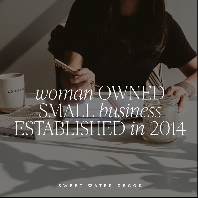 May include: A person writing with a pen on a desk with the text "woman OWNED SMALL business ESTABLISHED in 2014". A mug with "GO FOR IT" is on the left. A lit candle sits on the right. The brand name "SWEET WATER DECOR" is at the bottom.