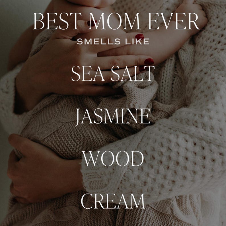 May include: A close-up image of a mother holding a baby. The text "BEST MOM EVER" is at the top of the image. The text "SMELLS LIKE" is below the first line of text. The text "SEA SALT", "JASMINE", "WOOD", and "CREAM" are stacked vertically below the second line of text.