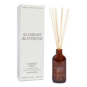 May include: A 3.5 fl oz amber glass reed diffuser bottle with light-colored wooden reeds and a white rectangular box. The box features the text Sweet Water Decor, Illuminate the Everyday, Pumpkin Spice, and Pumpkin, Cloves, Cinnamon & Vanilla.