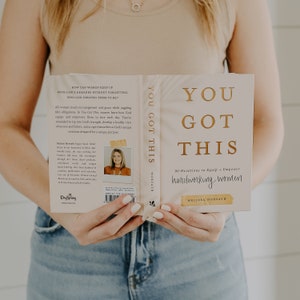 May include: A closed book titled "You Got This" with a gold title and subtitle. The subtitle is "90 Devotions to Equip + Empower Hardworking Women". The author is Melissa Horvath. The book cover is white with a gold border.