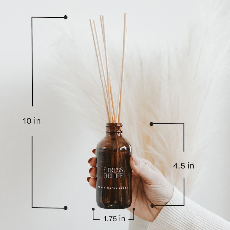 May include: An amber glass reed diffuser bottle with light-colored wooden reeds. The label reads STRESS RELIEF and SWEET WATER DECOR. Dimensions are 10 inches total height, 4.5 inches bottle height, and 1.75 inches in diameter.