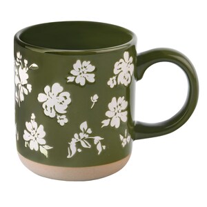 May include: A ceramic coffee mug with a dark green exterior and a light tan base. The mug is adorned with white floral patterns. The handle is a matching dark green. This mug is perfect for enjoying your favorite hot beverages.
