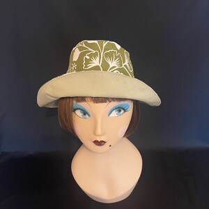 May include: A green and white floral print sun hat with a wide brim.