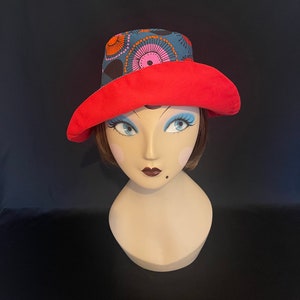 May include: A red and blue bucket hat with a colorful geometric pattern. The hat is made of fabric and has a wide brim.