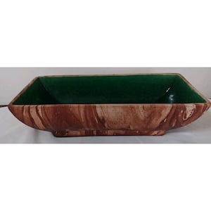 May include: A rectangular ceramic planter with a brown and cream marbled exterior and a deep green interior. The planter has a unique, angular shape and is suitable for indoor or outdoor use.