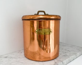 Bote de cobre vintage para harina con tapa, etiqueta y asa de latón, decoración de cocina rústica.