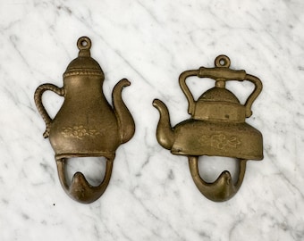 Par de ganchos de pared vintage de latón con forma de tetera para la cocina.