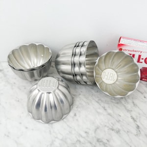 May include: Set of six vintage silver metal Jell-O molds. The molds are shaped like a dome with a fluted design. The molds are stacked on top of each other.
