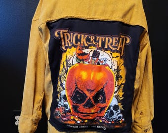 May include: Mustard yellow corduroy jacket with a black panel featuring a Halloween-themed graphic. The graphic includes a jack-o'-lantern, skulls, and the words "Trick or Treat." The text "Always check our candy" is also visible.