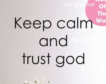 Op de afbeelding: Een witte muur met zwarte tekst die "Keep calm and trust god" luidt. Een roze cirkel met de tekst "State Of The Wall" bevindt zich in de rechterbovenhoek. Een vaas met witte bloemen staat op een tafel in de onderste helft van het beeld.