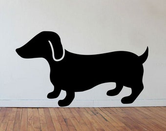 May include: A black silhouette of a dachshund dog on a white wall.