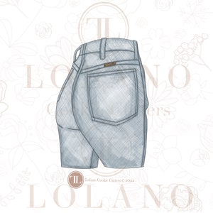 Op de afbeelding: Een lichtblauwe denim koekjesvormer in de vorm van een spijkerbroek. De koekjesvormer heeft een achterzak en een tailleband. De koekjesvormer staat op een witte achtergrond met een bloemenpatroon.