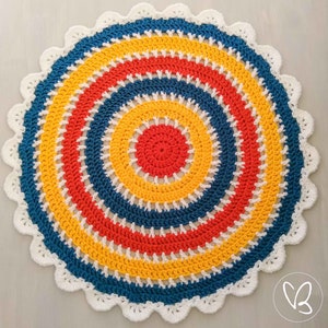 May include: A colorful crocheted round rug with a white border. The rug has concentric circles of red, yellow, and blue yarn.
