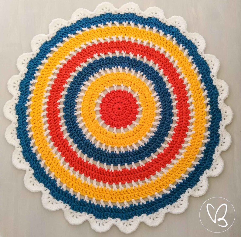 May include: A colorful crocheted round rug with a white border. The rug has concentric circles of red, yellow, and blue yarn.