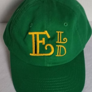 May include: A green baseball cap with a yellow embroidered "FLD" logo.