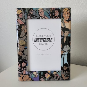 May include: A picture frame with a collage of comic book characters. The frame is made of wood and has a white mat. The text "Curse Your Inevitable Crafts!" is printed on the mat. The frame is designed to fit a 4x6 photo.