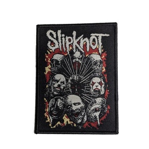 May include: Black and white embroidered patch with the band name "Slipknot" in white lettering. The patch features a red and yellow flame design with multiple black and white masked figures.