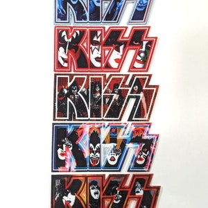 Puede incluir: Cinco parches diferentes del logotipo de la banda KISS con las caras de los miembros de la banda en las letras. Los parches son de diferentes colores, incluyendo azul, rojo, negro y naranja.