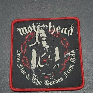 Könnte beinhalten: Schwarzer und roter gestickter Patch mit dem Text "Motörhead Iron Fist & The Hordes From Hell" und einem Schwarzweißbild einer Person, die Gitarre spielt.