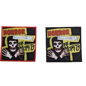 May include: Two black and yellow embroidered patches with the text "Horror Business The Misfits" and a skull-faced figure. The patch on the left has a red border and the patch on the right has a black border.