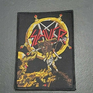 Op de afbeelding: Zwarte en gouden geborduurde patch met het woord "Slayer" in rode letters en een pentagram met zwaarden. De patch toont een demon met hoorns en een staart.