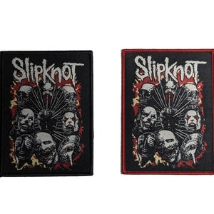 Puede incluir: Dos parches bordados negros y rojos con el nombre de la banda "Slipknot" y un gráfico de figuras enmascaradas.