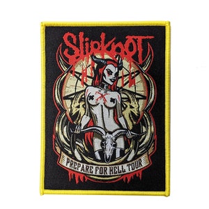 Op de afbeelding: Zwarte en gele geborduurde patch met een rode en witte illustratie van een vrouw met hoorns en een schedel. De tekst "Slipknot" en "Prepare for Hell Tour" is zichtbaar op de patch.