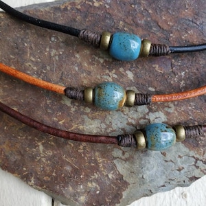 May include: Three leather cord necklaces with blue and brown ceramic beads and gold metal accents.