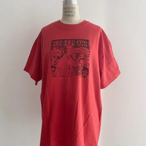 May include: Red t-shirt with a black and white graphic print of the band "Sub Humans" and the text "It's Revolution Time".
