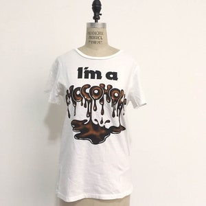 May include: White t-shirt with a graphic print of the text "I'm a Chocoholic" in black with brown dripping chocolate letters.