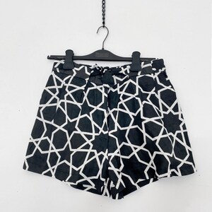 May include: Black and white geometric print shorts with a tie waist. The shorts have a star pattern.