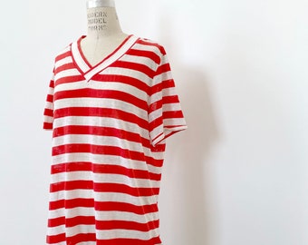 May include: Red and white striped t-shirt with a v-neck. The shirt is made of a lightweight fabric and has a relaxed fit.
