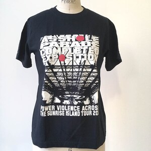 May include: Black t-shirt with a white graphic print of a bridge and the text "ASSHOLE PARADE COMPLETED EXPOSITION POWER VIOLENCE ACROSS THE SUNRISE ISLAND TOUR 20".