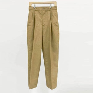 Puede incluir: Un pantalón de color caqui con pliegues, cierre de botón y trabillas para el cinturón.