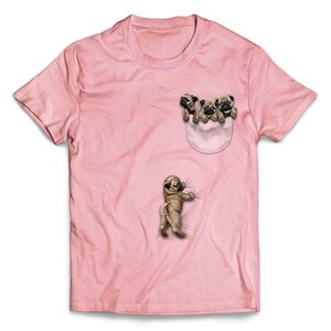 Könnte beinhalten: Pinkes T-Shirt mit einem Aufdruck von drei Mops, die aus einer Tasche schauen. Die Möpse sind braun und weiß.
