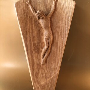 May include: A wooden sculpture of a person with arms outstretched, carved in a diamond shape.