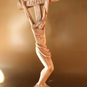 以下が含まれることがあります： 十字架にかけられたイエス・キリストの木製彫刻。彫刻は細部まで彫られており、十字架には「INRI」の文字が刻まれています。