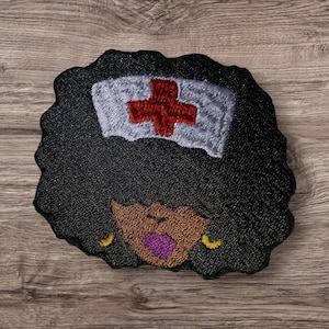 May include: Embroidered patch featuring a Black woman with a nurse's cap. The cap is white with a red cross. The woman has black hair, brown skin, purple lips, and gold earrings. The patch has a black, textured background.