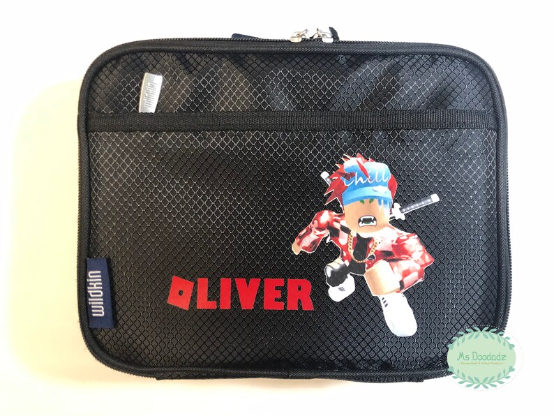 May include: Black rectangular Wildkin lunch bag with a zipper closure. The bag features a Roblox-style character graphic and the name "OLIVER" in red block letters. A small silver pen is in the front pocket.