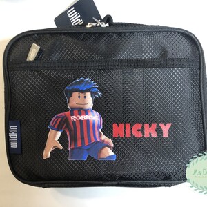 May include: Black lunch bag with a mesh design, featuring a Roblox character in a red and blue striped jersey. The name "NICKY" is printed in red. Includes a Wildkin tag.