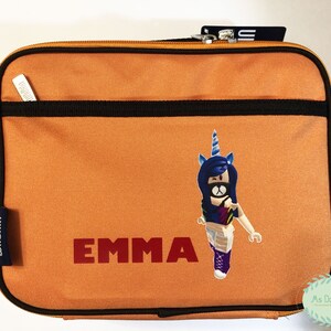 May include: Orange rectangular lunch bag with a black zipper and trim. The bag features the name "EMMA" in red block letters and a cartoon unicorn character. A small pocket is on the front.