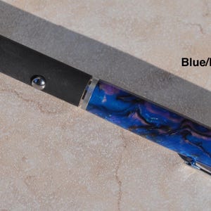 May include: A laser pointer with a black matte body, a silver button, and a blue and purple marbled acrylic barrel. The device features a silver tip with a warning label that reads DANGER and includes the text Blue/Purple on the side.