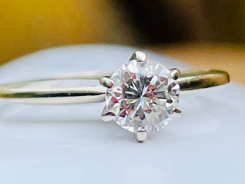 Puede incluir: Un anillo de plata con un solitario redondo de diamante transparente.